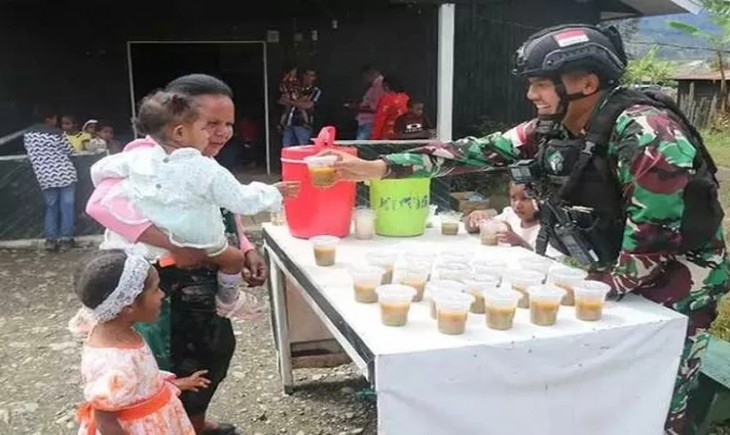Satgas Yonif Raider 303 Kostrad membagikan bubur kacang hijau buat anak-anak di Puncak Papua. (Penkostrad)